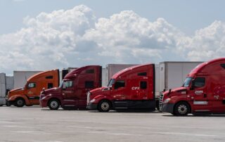 A line of commercial semi-trucks parked at a rest stop, representing out-of-state tractor-trailers involved in Pennsylvania limited tort insurance claims.