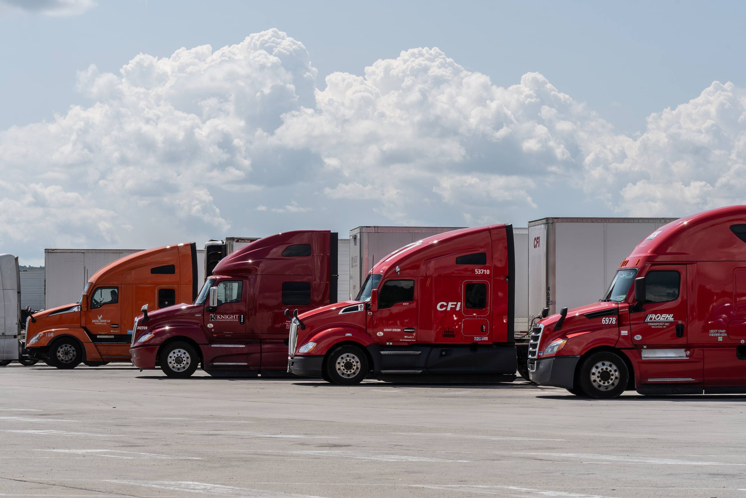 A line of commercial semi-trucks parked at a rest stop, representing out-of-state tractor-trailers involved in Pennsylvania limited tort insurance claims.