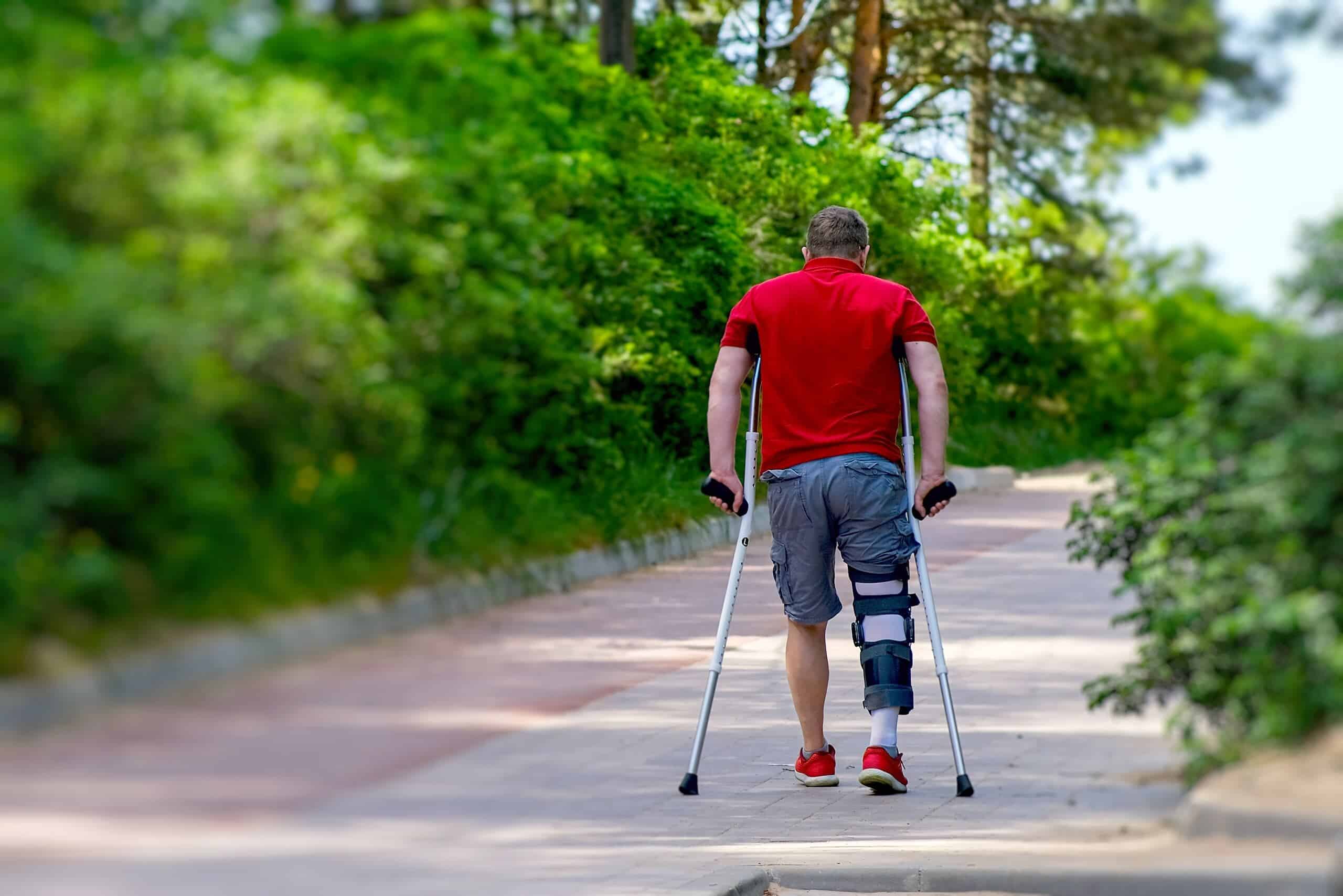 A man using crutches and wearing a leg brace while walking outdoors, illustrating the serious injuries handled by our Philadelphia personal injury lawyers.