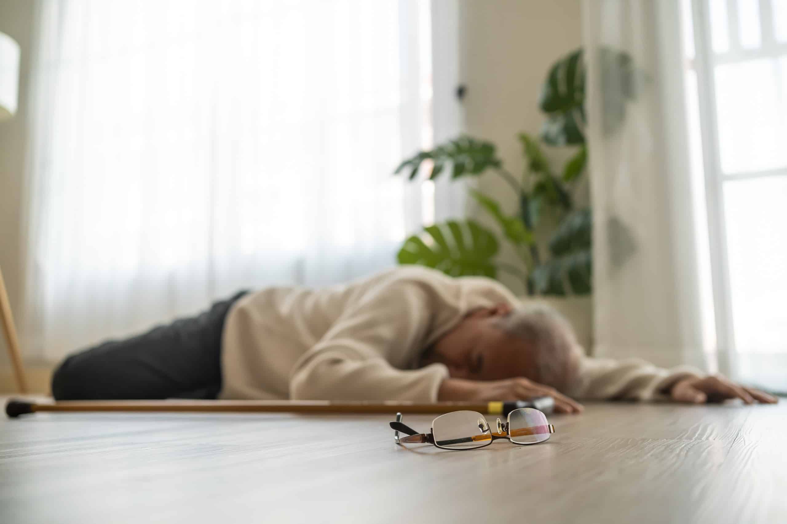 An elderly person lying on the floor after a fall with their cane and glasses nearby, illustrating the impact of slip and fall injuries in Pennsylvania.