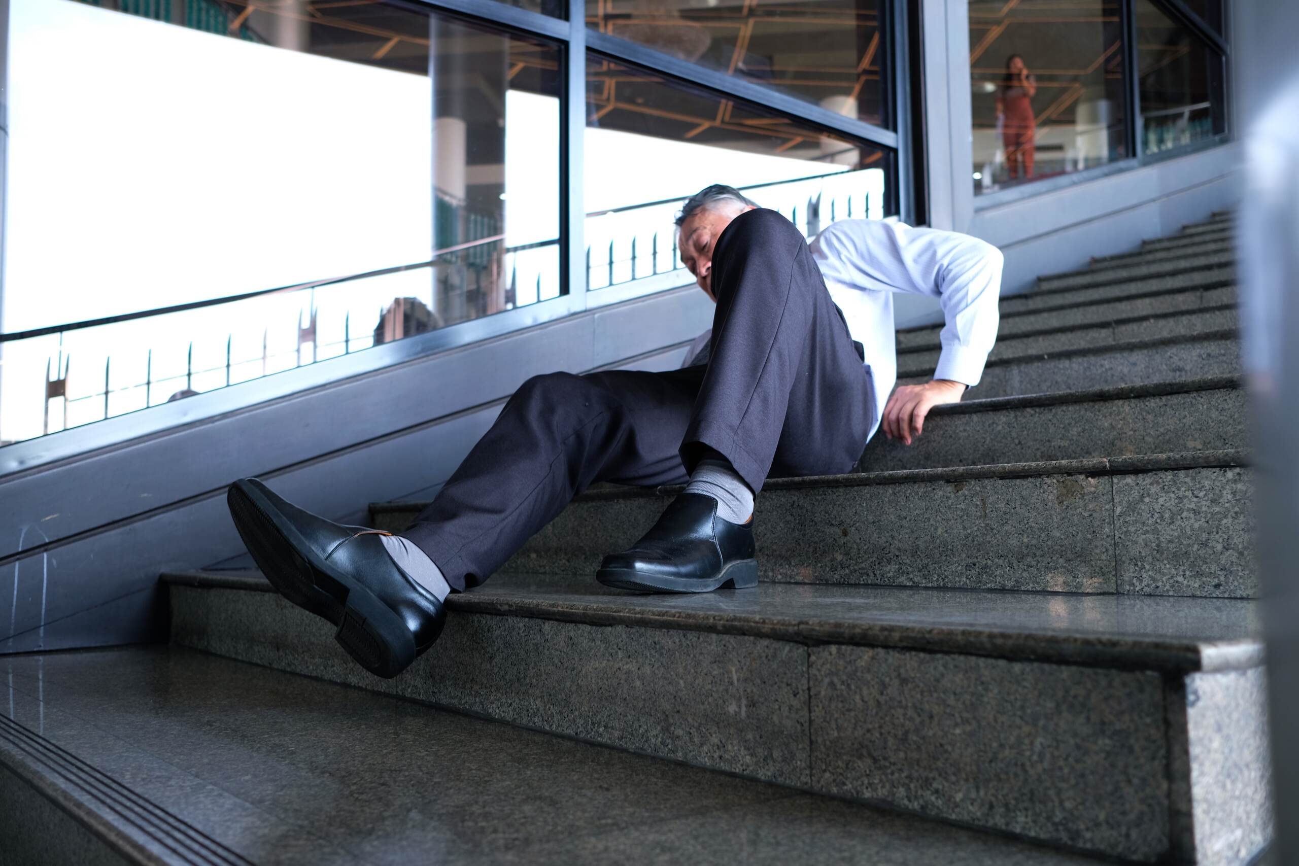 An individual sitting on outdoor concrete stairs after a fall in Scranton, illustrating a premises liability accident caused by negligent property maintenance.