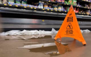 An orange caution sign placed next to a large liquid spill on a Scranton grocery store floor, illustrating how constructive notice is proven in Pennsylvania slip and fall cases.