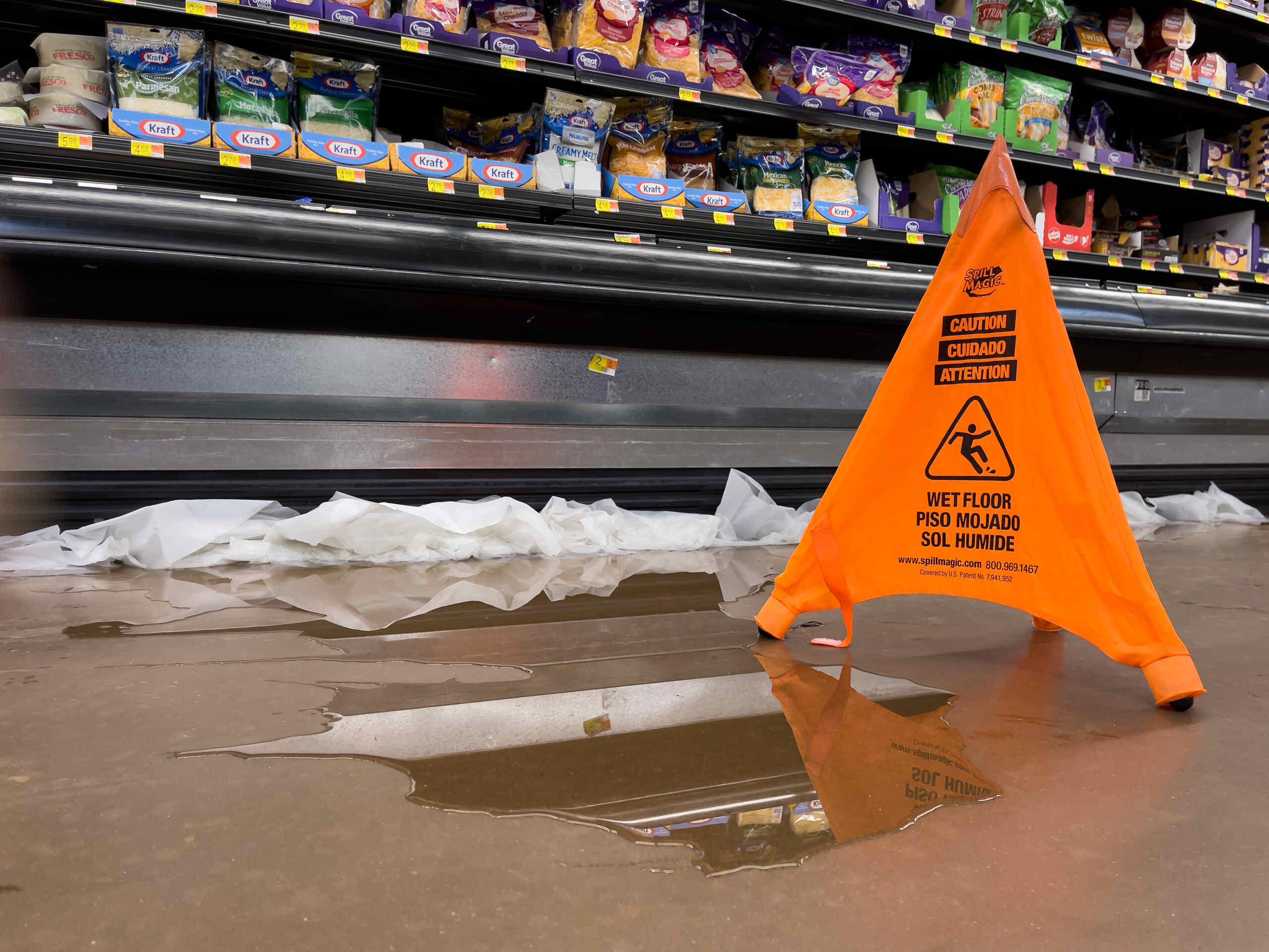 An orange caution sign placed next to a large liquid spill on a Scranton grocery store floor, illustrating how constructive notice is proven in Pennsylvania slip and fall cases.