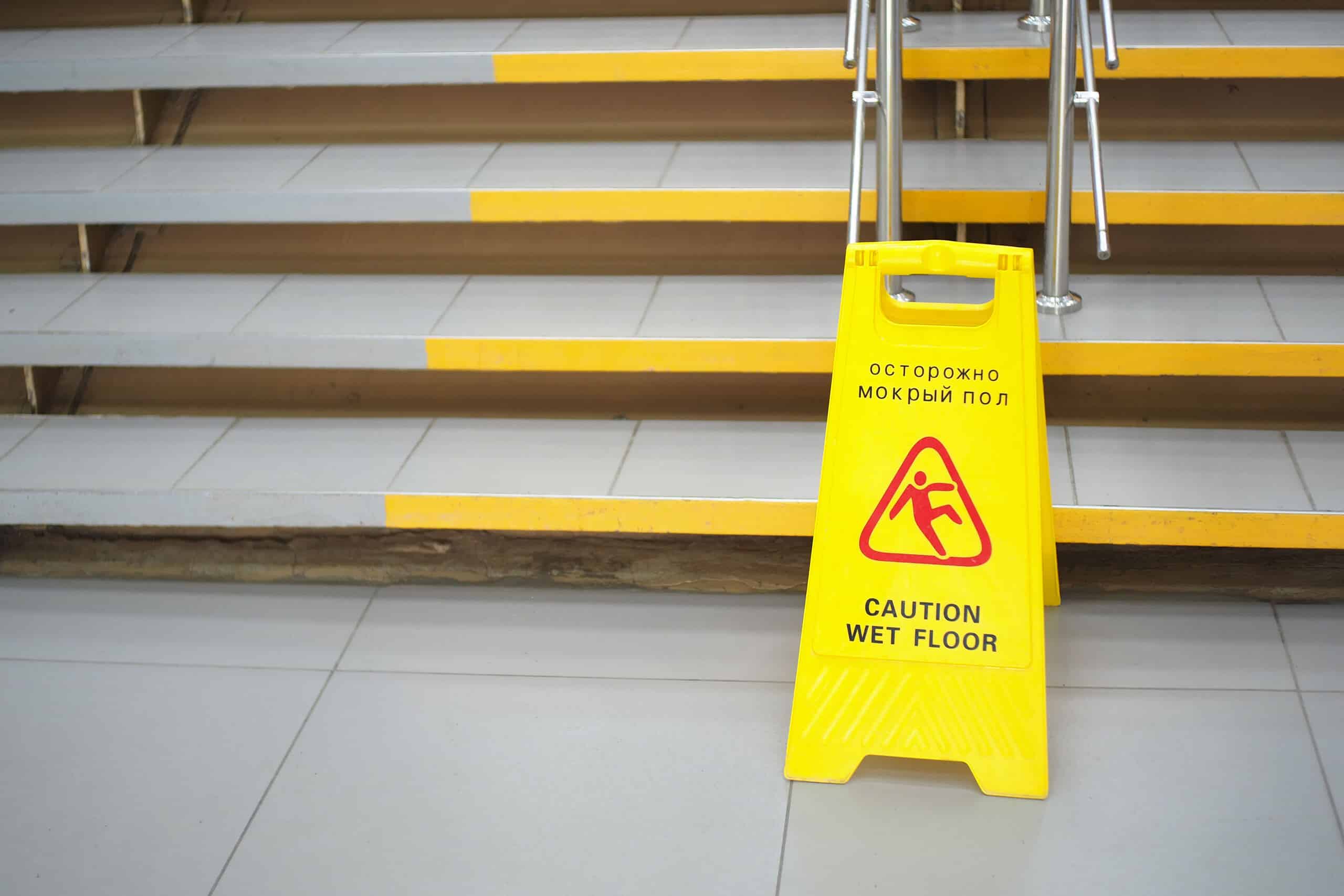 A yellow wet floor warning sign at the base of tiled stairs, representing a business's duty to inspect for hazards and the legal requirements for slip and fall claims in Scranton.