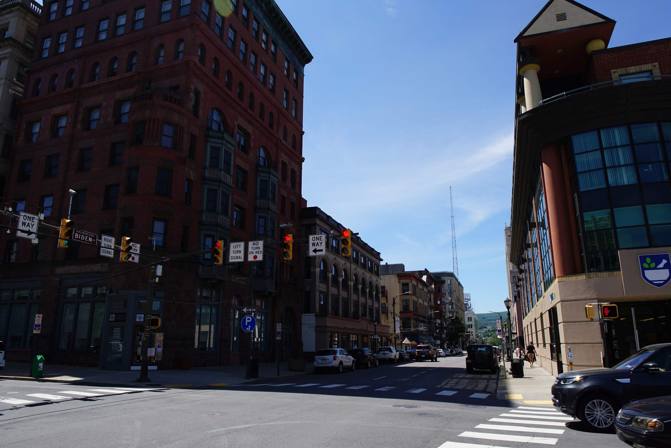A downtown city intersection with traffic lights, crosswalks, and brick buildings under a clear blue sky, highlighting an area served by Scranton bicycle accident lawyers.
