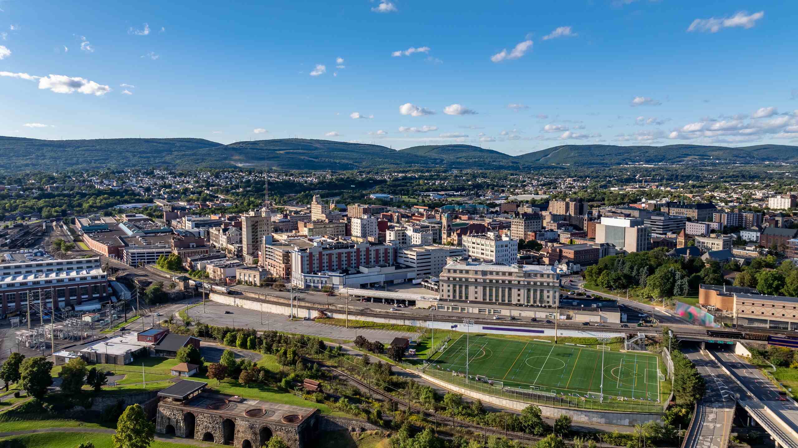 An aerial view of Scranton, Pennsylvania showing the downtown cityscape, a green athletic field, and surrounding mountains, representing the region served by Scranton distracted driving accident lawyers.