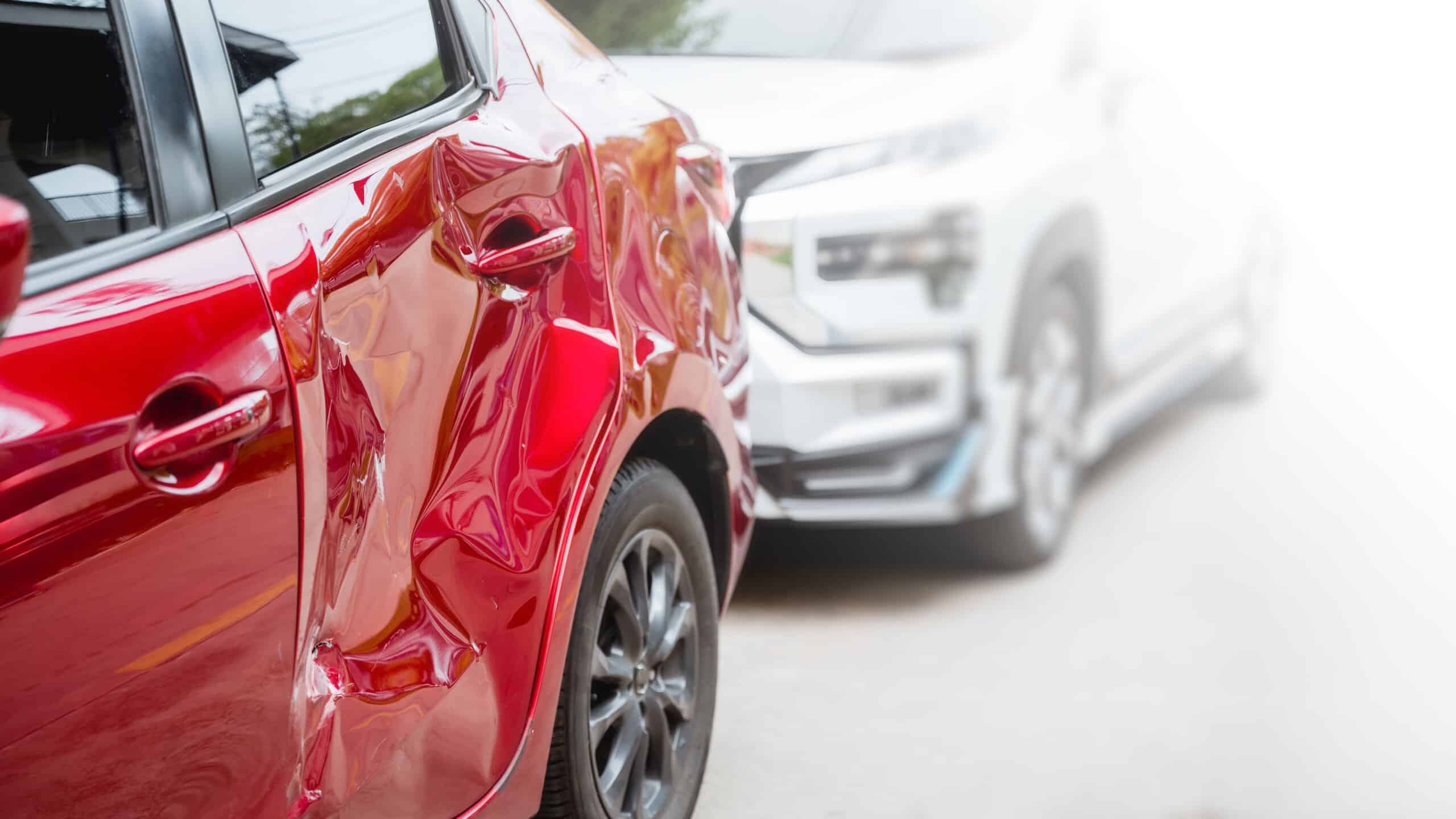 A close-up of a red car with a heavily crushed side door following a side-impact collision, representing vehicle damage claims handled by Scranton Hit and Run Accident Lawyers.