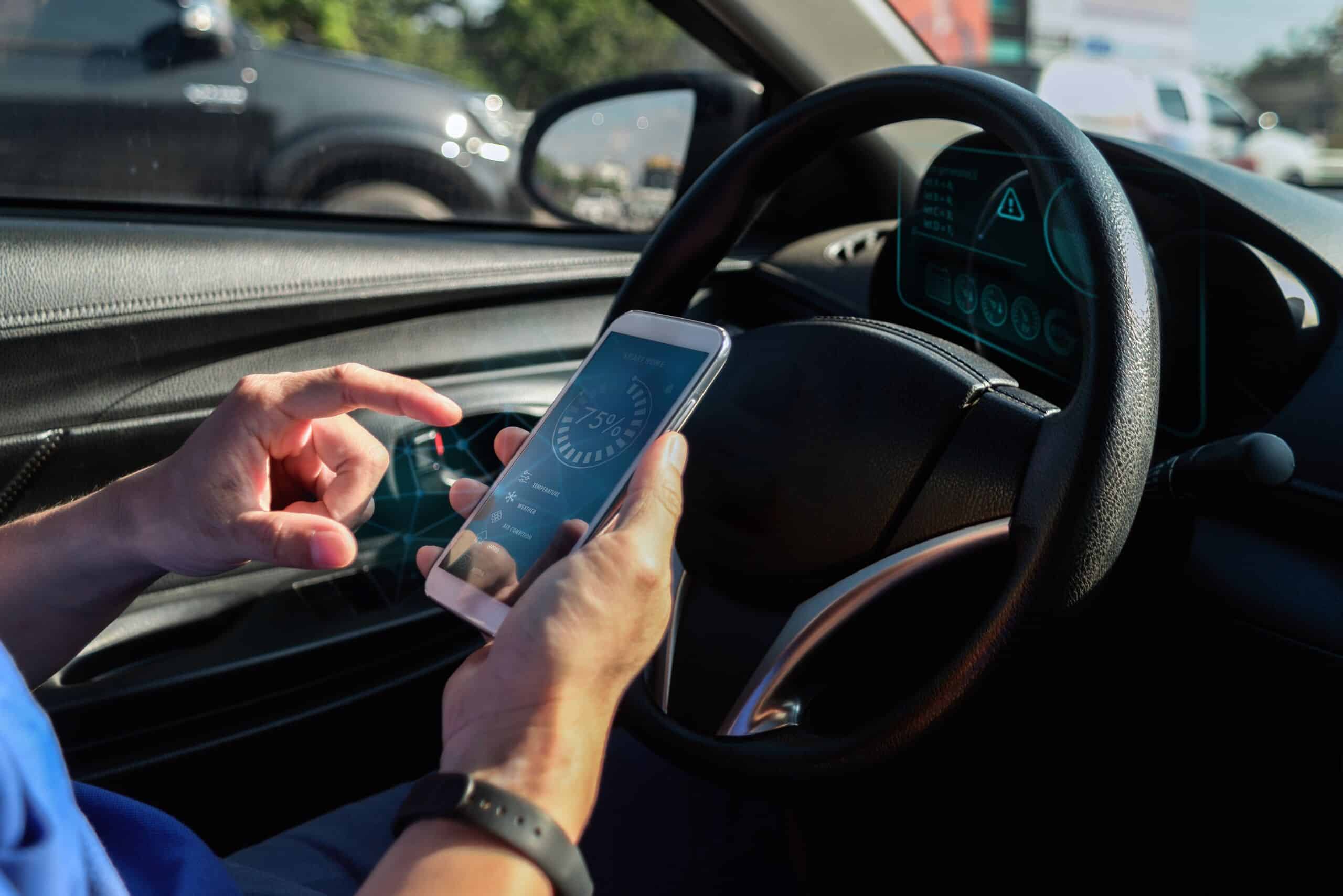 Driver using a smartphone at the steering wheel in traffic.
