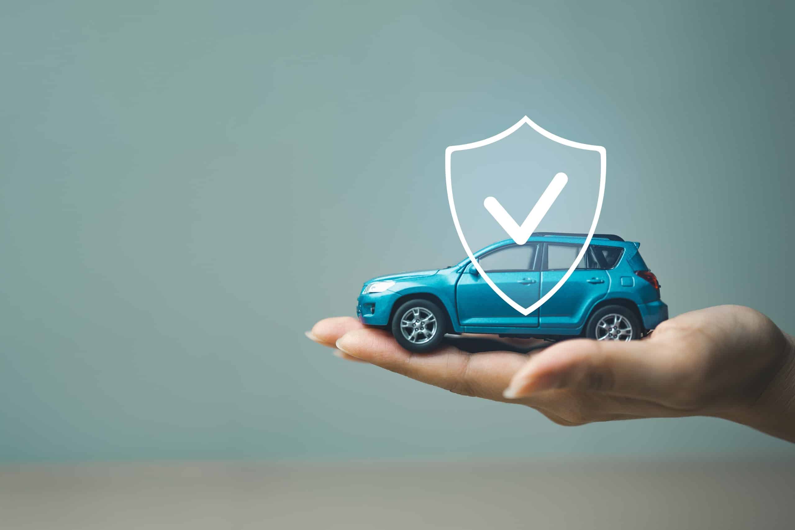 Hand holding toy car with insurance shield icon