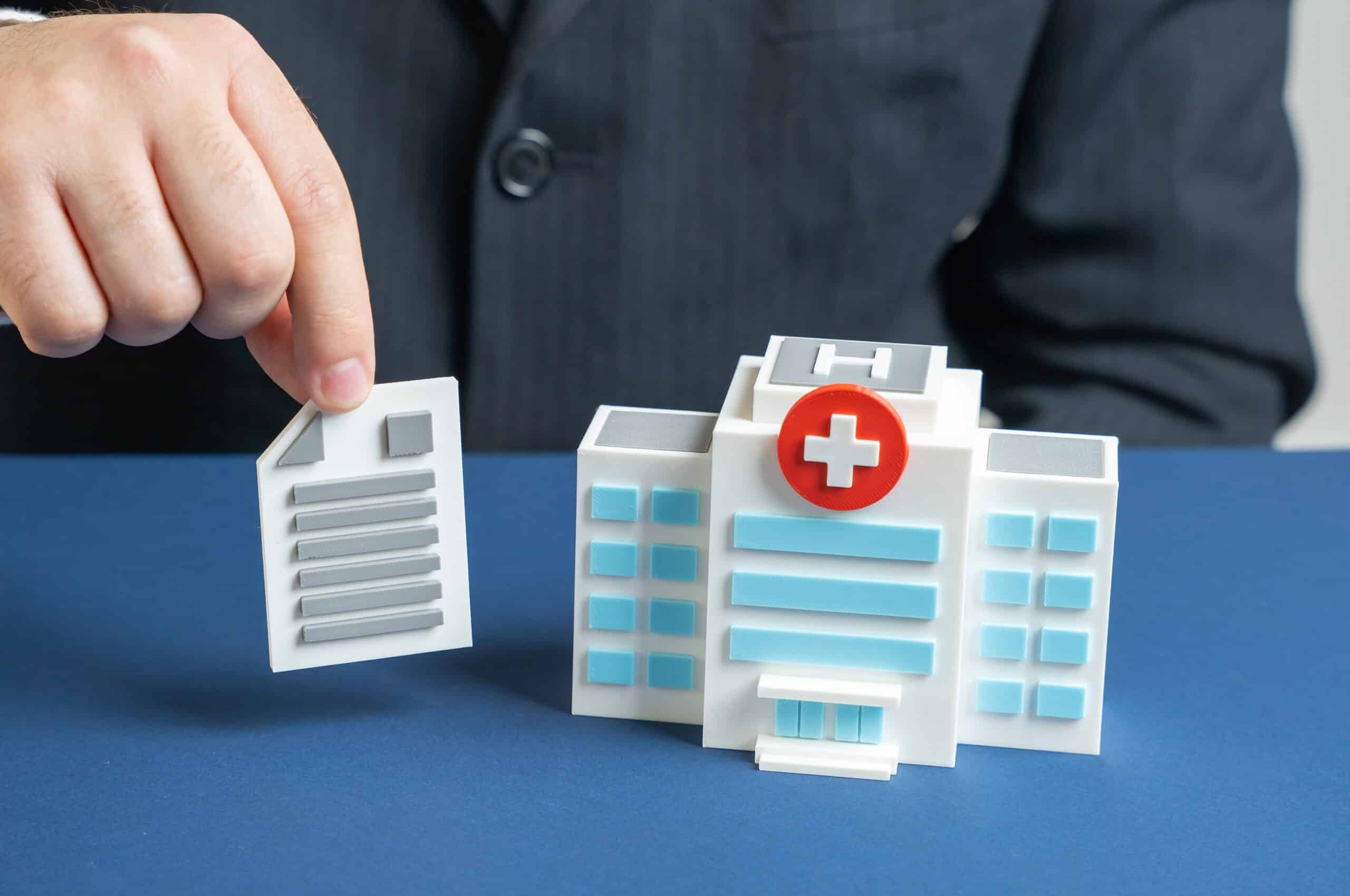 A person placing a medical document next to a toy hospital building illustrates injury claim evidence gathered by Allentown personal injury lawyers.
