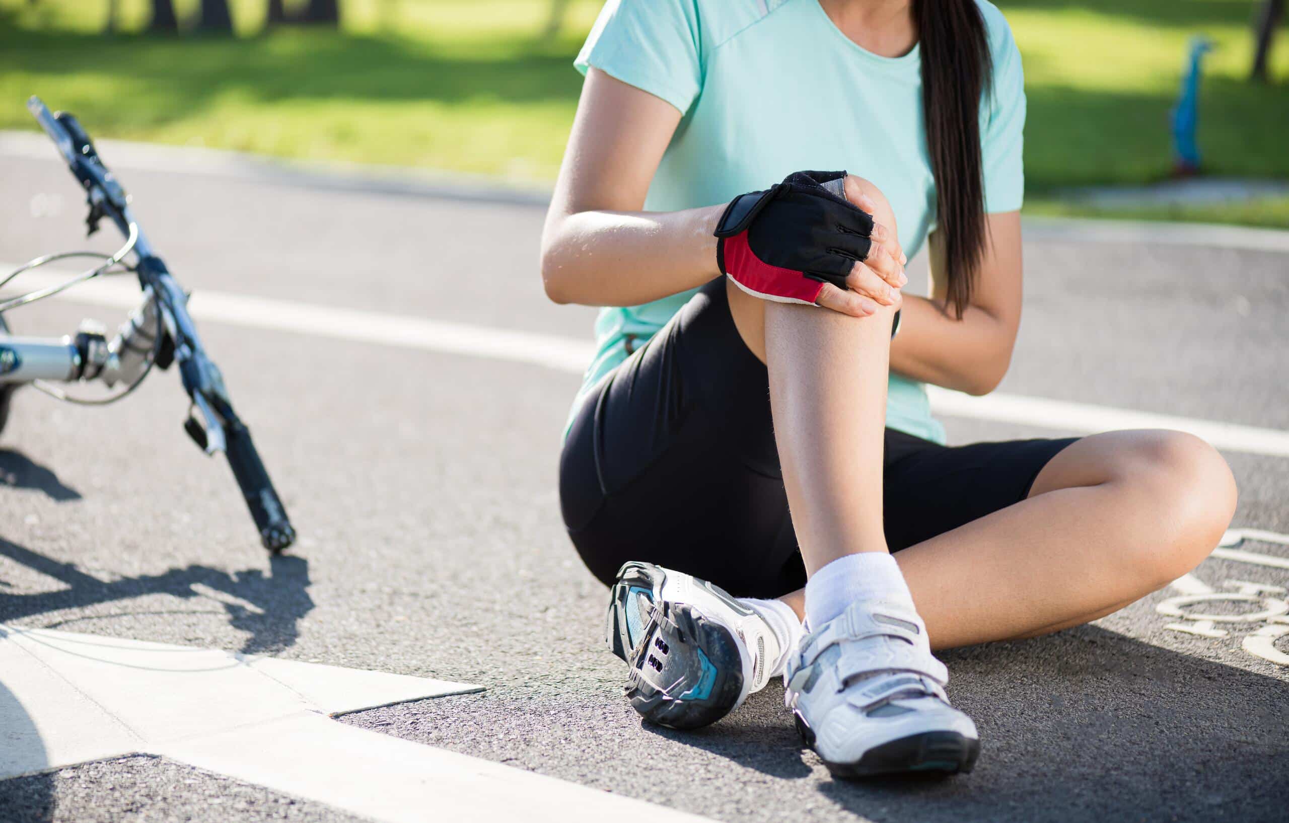 Injured cyclist holding her knee next to a fallen bike represented by Pennsylvania bicycle accident lawyers.
