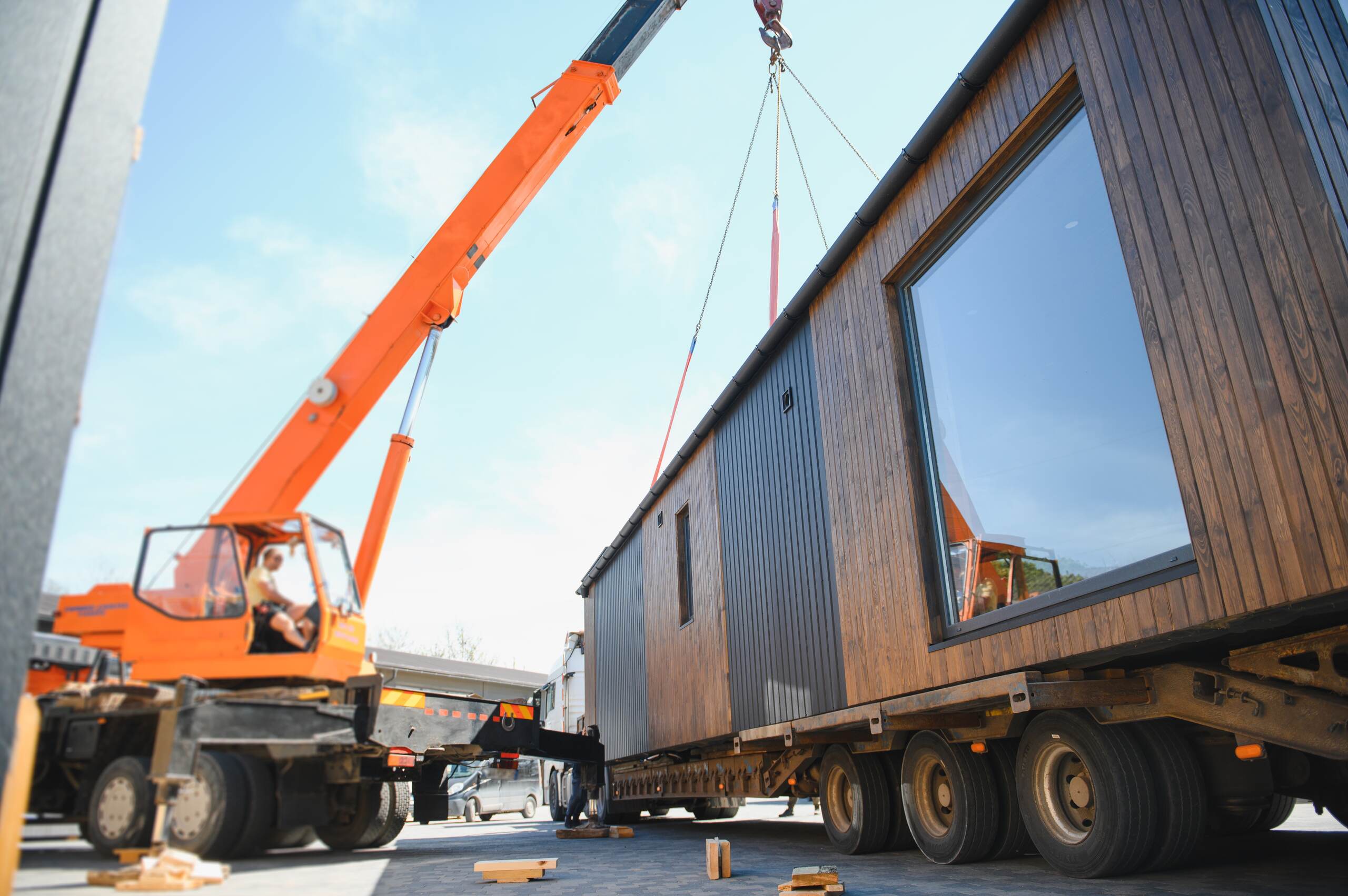 An orange crane maneuvering heavy equipment on a job site represented by Philadelphia construction accident lawyers.