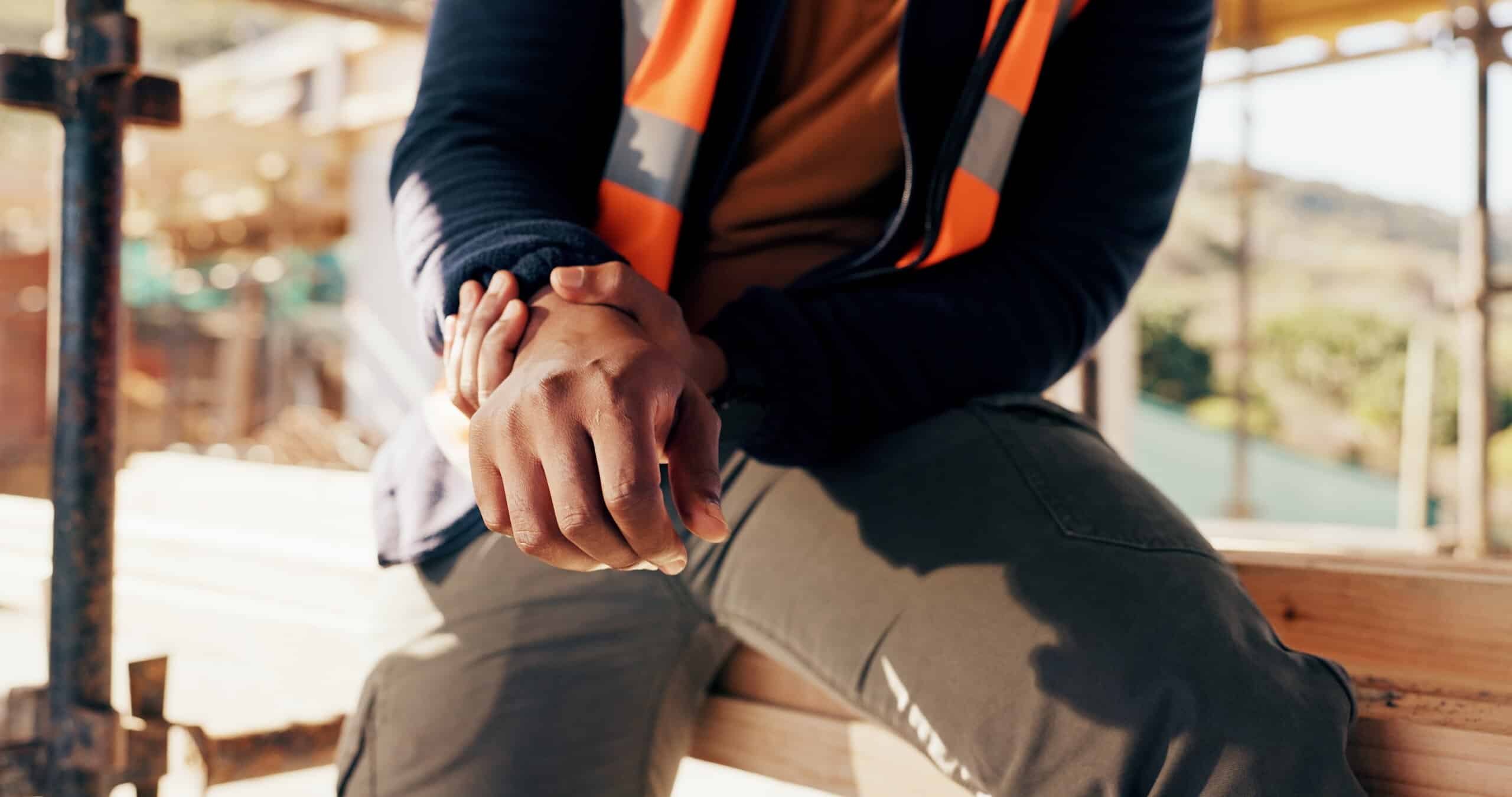 A construction worker in a safety vest holding his injured wrist for a case handled by Philadelphia construction accident lawyers