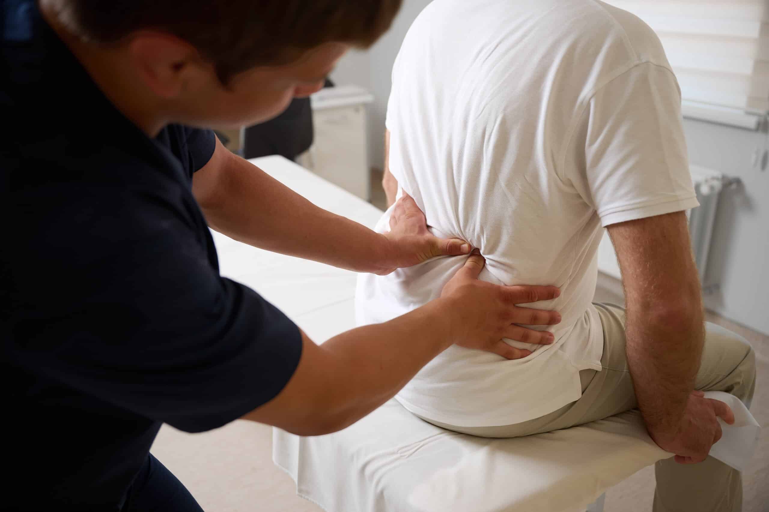 A physical therapist examining a patient lower back during treatment evaluated by Philadelphia spinal cord injury lawyers.