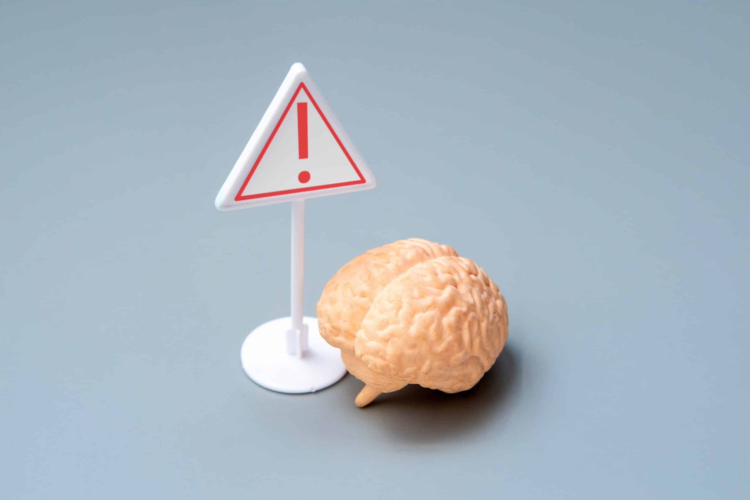 A brain model next to a warning sign symbolizing claims managed by Philadelphia traumatic brain injury lawyers.